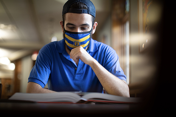 葡京官方下载网站的学生在课桌上，戴着面具