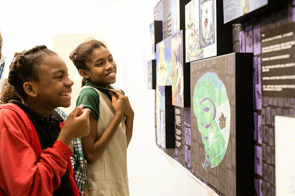 two African girls looking and smiling at colorful artwork on a wall