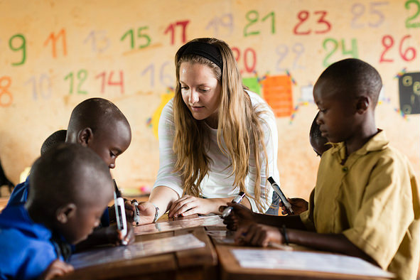 young professor teaching African children at their desks